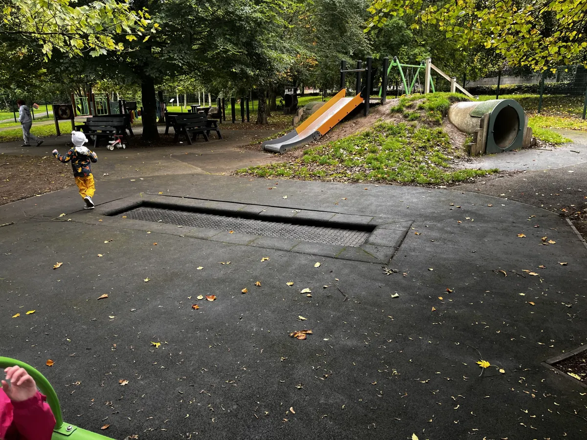 The sunken trampoline at the sensory playground in Mulcahy Park, Clonmel, with a slide and tunnel built into a grassy mound behind it